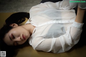 A woman laying on the ground with her head resting on her hands.