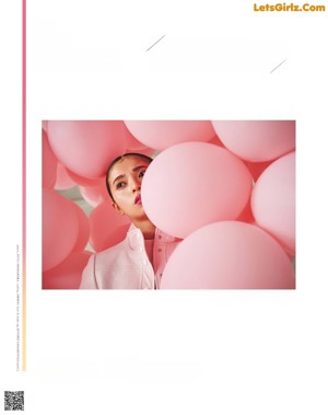 A woman standing in front of a bunch of pink balloons.