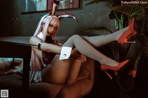 A woman in fishnet stockings and bunny ears sitting on a couch.