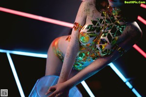 A woman in a bikini and high heels standing on a stool.