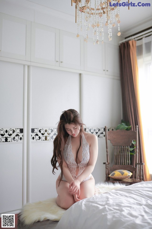 A woman sitting on a bed in a white lingerie.