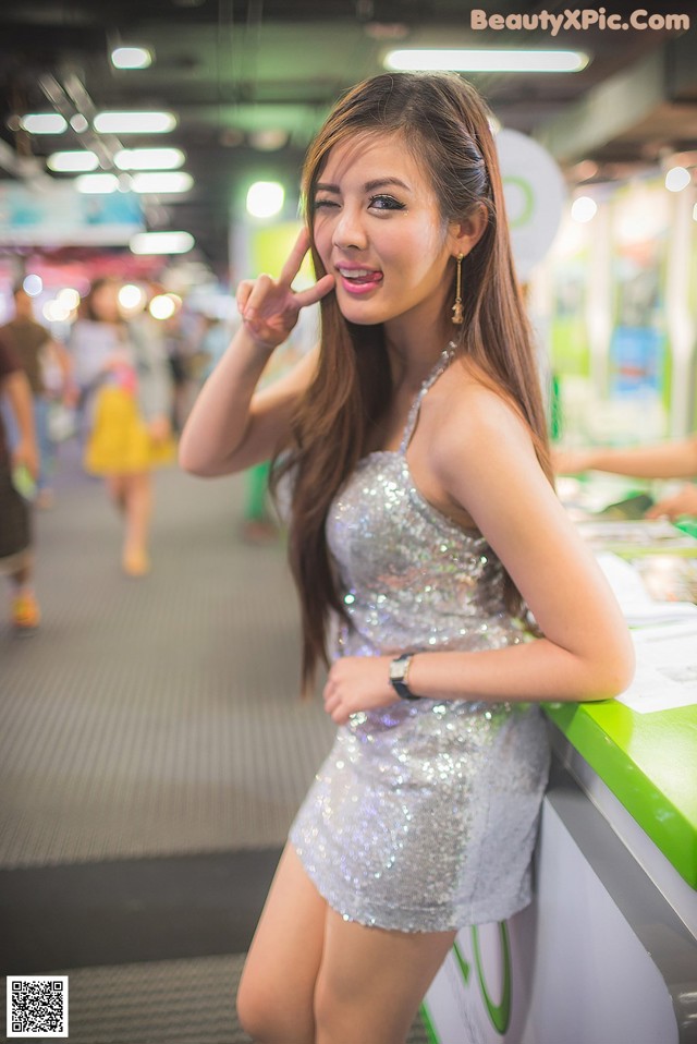 A woman in a silver dress standing next to a counter.