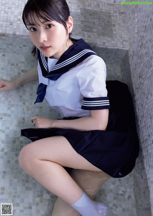 A woman in a school uniform sitting in a bathtub.