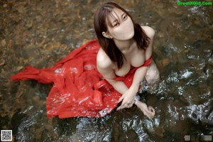 A woman in a white bodysuit posing in the woods.