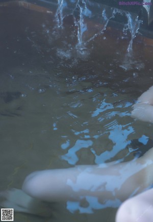 A naked asian woman sitting in a bathtub with her hands on her knees.