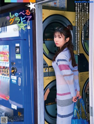 A woman holding a drink in front of a vending machine.