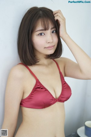 A woman in a red sweater sitting on a bed.