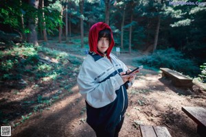 A person standing in the woods wearing a jacket.