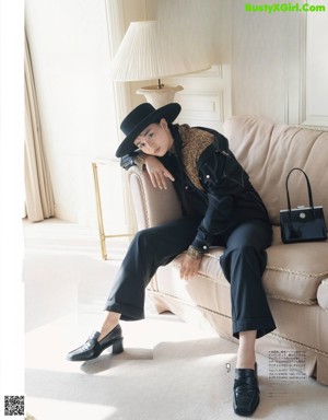 A woman sitting on a couch wearing a black and white hoodie.