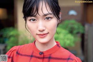 A woman in a red shirt is posing for a magazine.