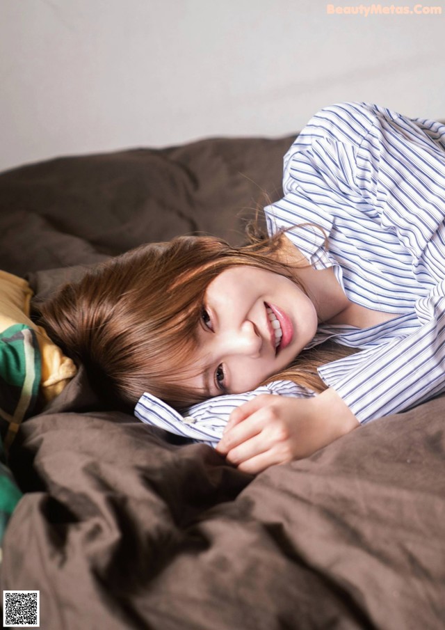 A young woman laying on a bed with her eyes closed.