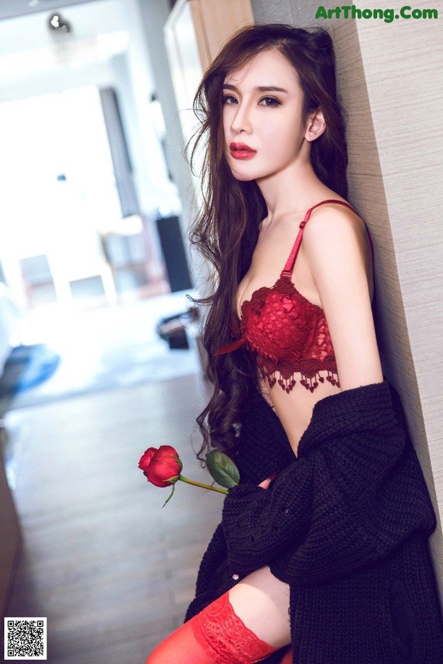 A woman in a red lingerie leaning against a wall.