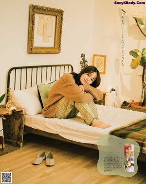 A woman sitting on a couch holding a plate of food.