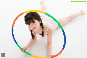 A young girl in a pink leotard leaning against a wall.