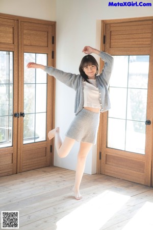 A woman in a blue sweater leaning on a wooden table.