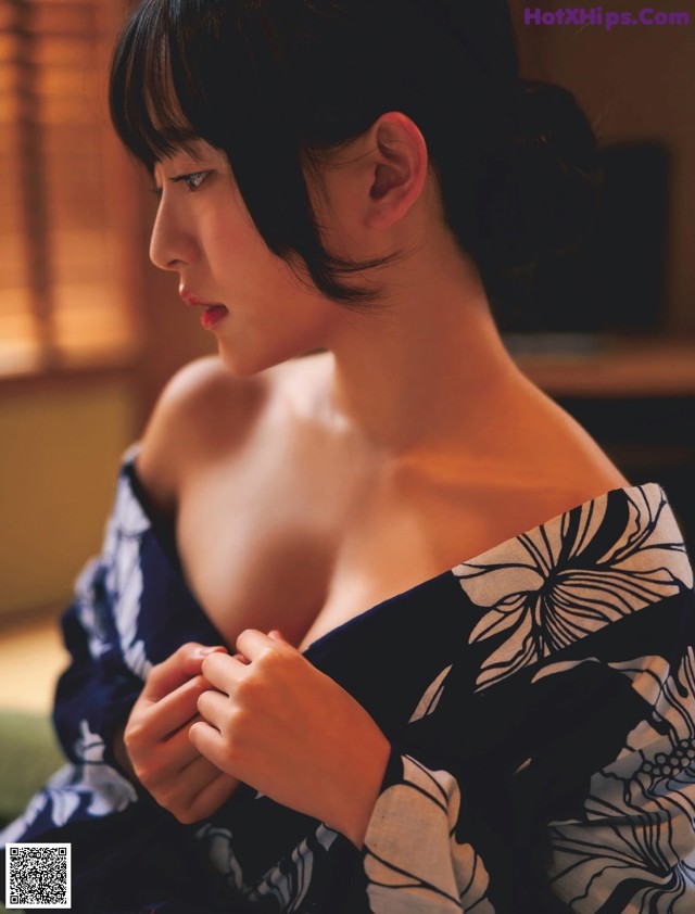 A woman in a blue and white kimono sitting on a couch.