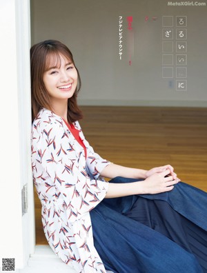 A woman in a blue dress standing in front of a desk.