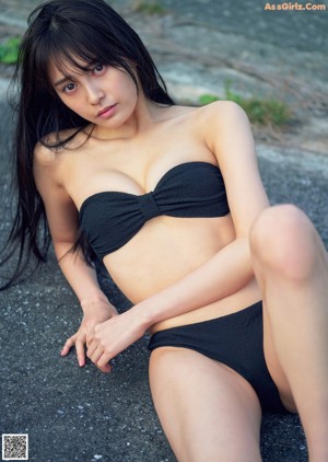 A woman in a school uniform is sitting on a rock.