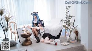A woman in a maid outfit sitting on a chair.