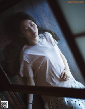 A woman laying on top of a couch next to a window.