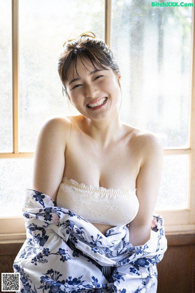 A woman sitting in front of a window covered in a blanket.