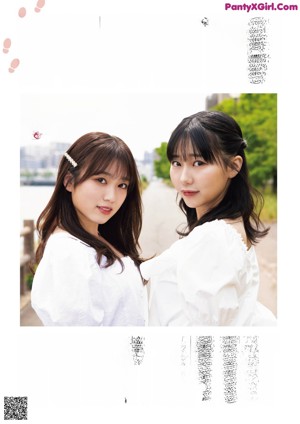 Two young women standing next to each other on a brick walkway.