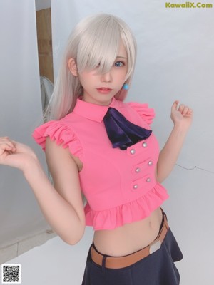 A woman in a pink shirt and blue skirt posing for a picture.