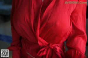 A woman in a red robe sitting on a couch.