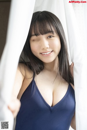 A woman in a white bikini leaning against a wall.