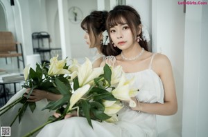 A woman in a white dress holding a bouquet of flowers.