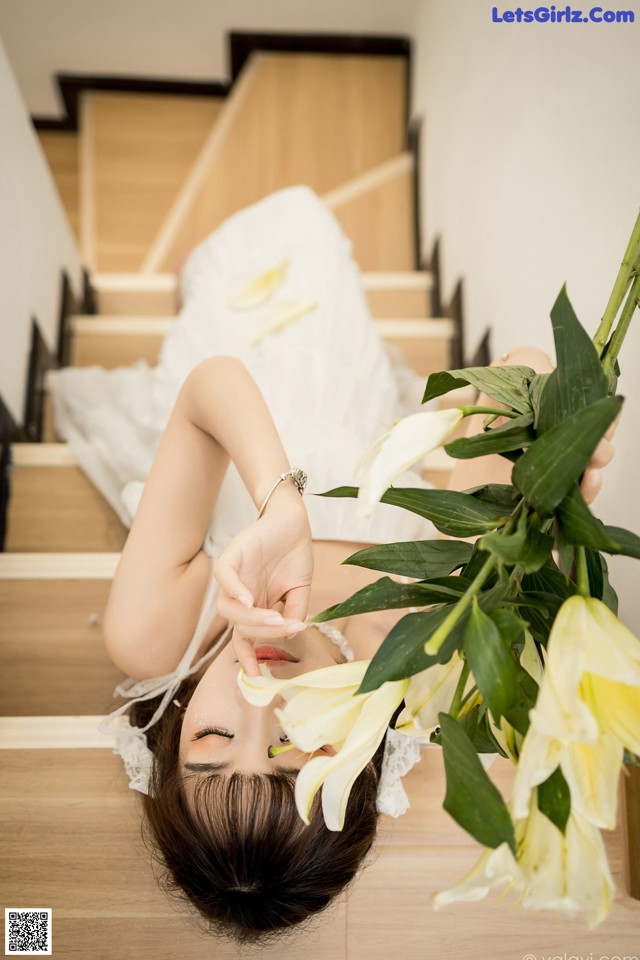 A woman laying on the stairs with a bouquet of flowers.