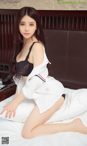 A woman in a white lingerie sitting on a chair.