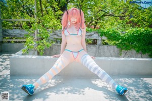 A woman with pink hair sitting on a wooden bench.