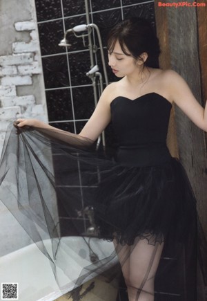 A woman in a black dress sitting on the floor.