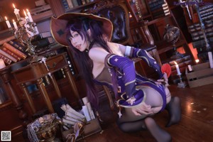 A woman in a witch costume is posing in front of a bookshelf.