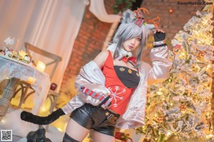 A woman sitting on the floor in front of a Christmas tree.
