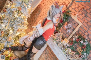 A woman sitting on the floor in front of a Christmas tree.