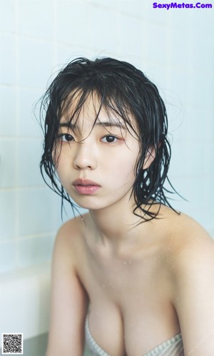 A woman with wet hair laying in a bathtub.