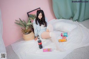 A woman in a blue hooded pajamas sitting on a bed.
