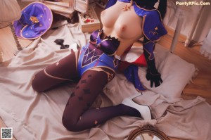 A woman in a blue and red outfit is posing on a bed.